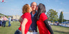 Two women in red tshirts kiss a man on the cheeks