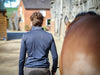 Man stood next to a horse, taken from the back
