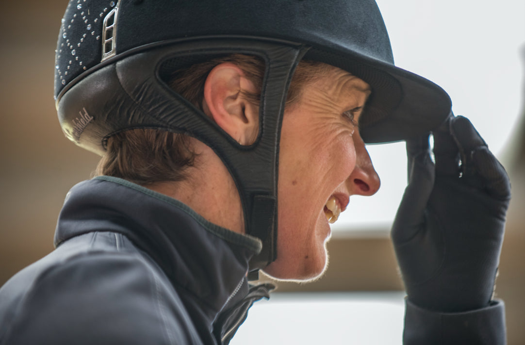 Side view close up of a person wearing a riding helmet and smiling