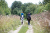Front view of two people slowly riding horses through the countryside
