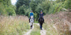 Two horses being ridden while strolling through the countryside
